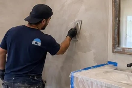 Illustrative artisan finishing microcement beside a bathroom vanity