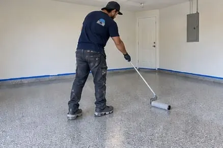 Illustrative worker rolling an epoxy coating on a garage floor