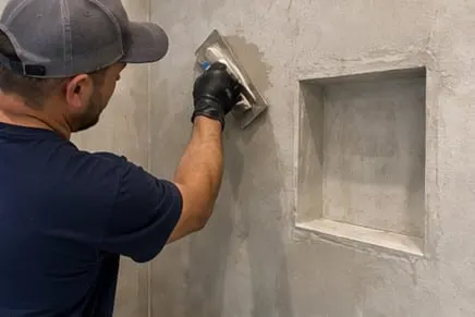Illustrative hand application of microcement around a shower niche