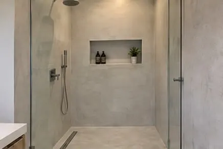 Illustrative walk-in shower with microcement walls and a recessed niche